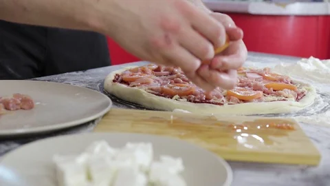 Hands of man put tomatoes and cheese on pizza dough with meat Video stock 128047575