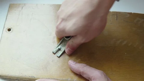 Hands of man removing hammered nail from wooden board with claw hammer closeup. Stock Footage 330543312