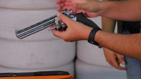 Hands of a man seen loading bullets into a revolver gun 動画素材 233557363