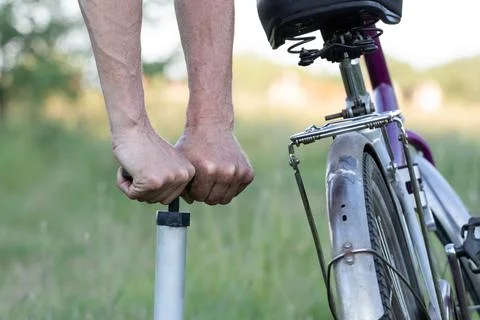 Hands of a man seen pumping a bicycle tire using a stand alone hand pump. P.. Stock Photos