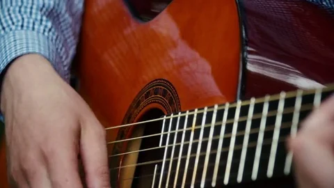 Hands of a man sitting on the grass and playing an acoustic guitar. Stock Footage 70876992