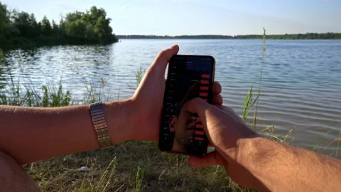 Hands of a Man with a Smartphone and Cryptocurrency Near the River in Nature Stock Footage 198140230