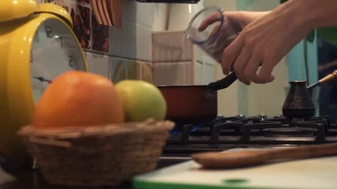 Hands of man smash grain out cup meal cooking in pot on stove in kitchen Stock Footage 83090616