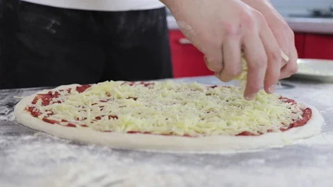 Hands of man sprinkle cheese on dough for pizza with tomato paste close up Video stock 127689668