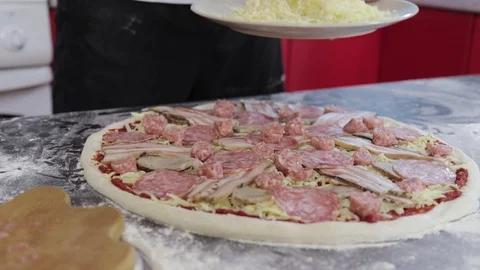 Hands of man sprinkle cheese on dough for pizza with tomato paste close up Video stock 127694596