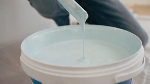 The hands of a man with a stick stir the paint in a bucket Blue paint drips into Video stock 152887416