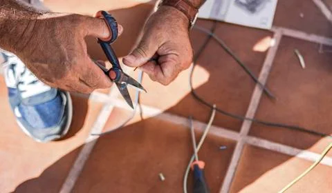 Hands of a man stripping cable to make electrical connections Stock Photos