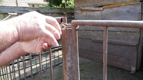 Hands of a man tying with a wire to a gate does not open Stock Footage 71175444
