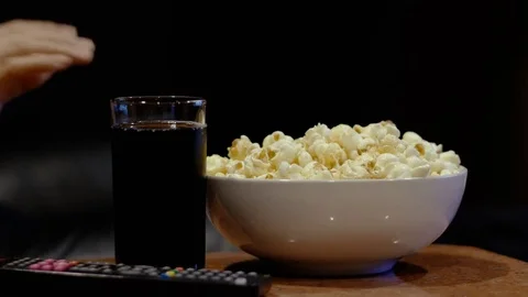The hands of a man use remote television and then pick up the popcorn Stock Footage 82010986
