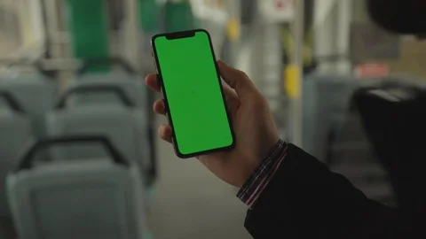 Hands man uses holding a mobile phone with a vertical green screen background Stock Footage 117943912