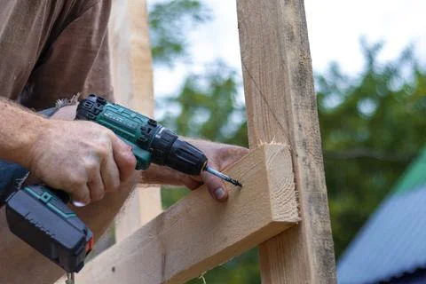Hands of man using drill to assemble wooden structure. Precision and skill re Foto stock