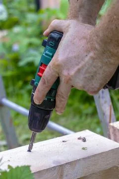 Hands of man using drill to assemble wooden structure. Precision and skill .. Stock Photos