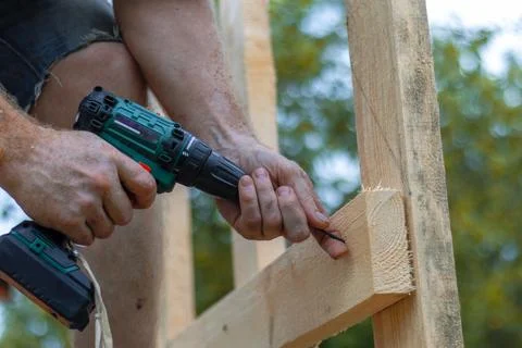 Hands of man using drill to assemble wooden structure. Precision and skill .. Stock Photos
