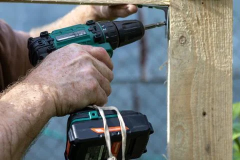 Hands of man using drill to assemble wooden structure. Close-up Stock Photos