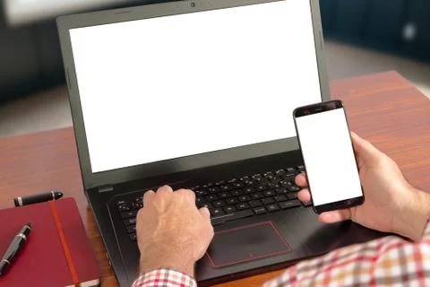 Hands of a man using a laptop an a mobile phone with blank screen Stock Photos