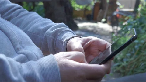 The hands of a man using a Smartphone writes text. Foreground. Closed plane Stock Footage 129420773
