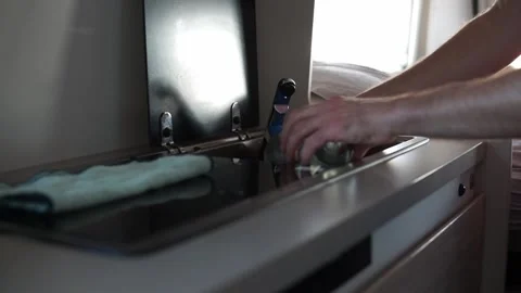 Hands of man washing a plastic cup in a RV motorhome sink. Water consumption Stock Footage 257898065