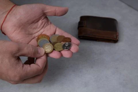 Hands of a man who are counting metal coins on the palm and a leather wallet Stock Photos