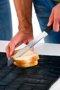 Hands of a man who cuts the bread Stock Photos