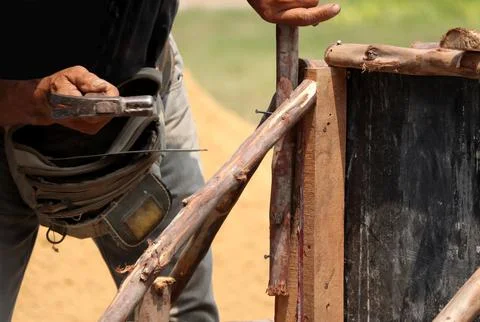 Hands of man working in construction site nailing in the wood with a hammer. Stock Photos