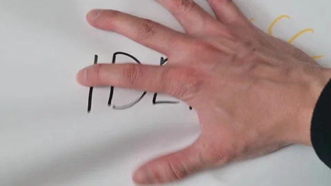 Hands manipulate and crumple white paper featuring the word 'idea' with a light Stockbeeldmateriaal 337550758