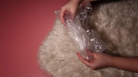 Hands manipulating a clear plastic bag with a white fluffy surface in the Stock Footage 339178283