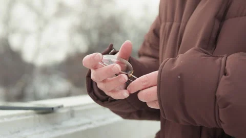 Hands manipulating dried twig while wearing brown padded jacket in cold outdoor Stock Footage 343528139