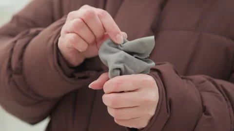 Hands manipulating small fabric pouch and keyring while wearing quilted winter Stock Footage 343532594