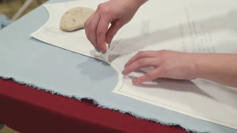 Hands mark fabric with a white chalk stick. Fabric rests on a red ironing b.. Stock Footage 340040079