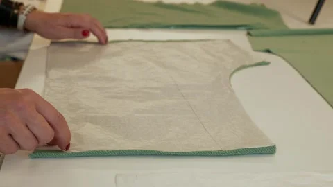 Hands marking a pattern on fabric at a worktable Stock Footage 348149085