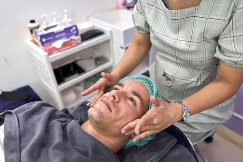 Hands massaging the face of a patient before getting a facial beauty treatment Stock Photos