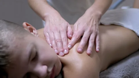 Hands of the Masseur are Massaging Back of a Teenager, a Child in a Spa Salon Stock-Footage 166466973