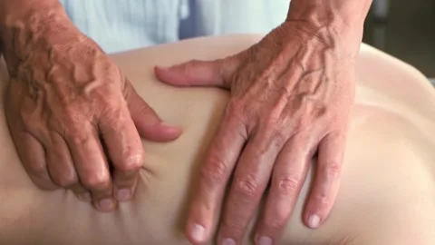 Hands of a masseur are massaging back of a child. A session of therapeutic Stock Footage 313938203