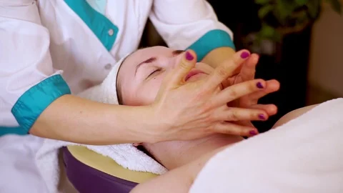 Hands of the masseur knew how to do a facial massage to the girl lying with Stock Footage 122281418