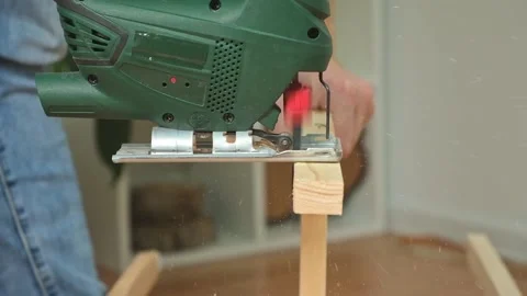The hands of a master carpenter with an electric jigsaw in his hands cutting off Stock Footage 220219424