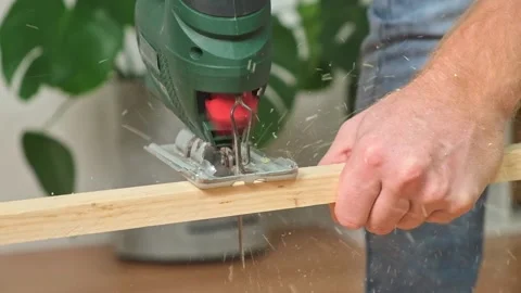The hands of a master carpenter with an electric jigsaw in his hands cutting off Stock Footage 229928218