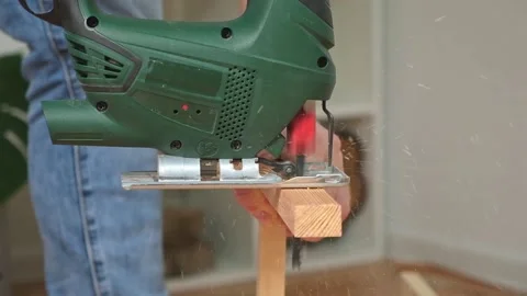 The hands of a master carpenter with an electric jigsaw in his hands cutting off Stock Footage 229928287