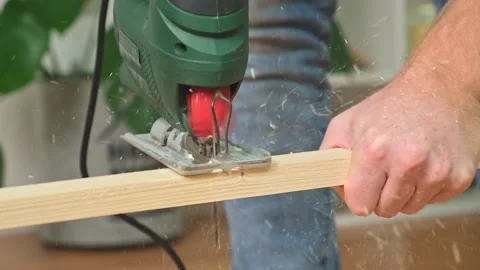 The hands of a master carpenter with an electric jigsaw in his hands cutting off Stock Footage 230721315