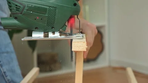 The hands of a master carpenter with an electric jigsaw in his hands cutting off Stock Footage 230721751