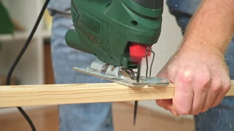 The hands of a master carpenter with an electric jigsaw in his hands cutting off Stock Footage 231185351