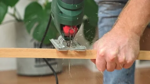 The hands of a master carpenter with an electric jigsaw in his hands cutting off Stock Footage 231518332