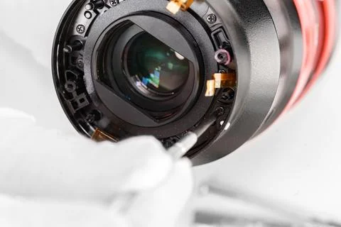The hands of the master with gloves and a broken lens of a professional camer Stock Photos