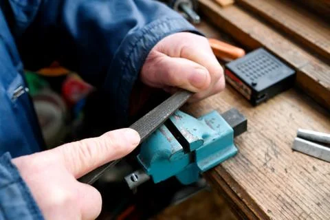 The hands of the master hold the file. Workplace, clamp visible, vice Foto stock
