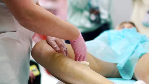 Hands of master in latex gloves remove sugaring paste from a leg in beauty salon Stockbeeldmateriaal 257251407