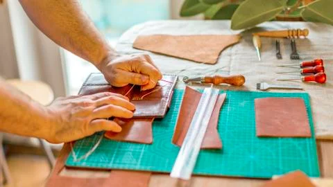Hands of the master. Marking and slicing red leather for making leather goods Foto stock