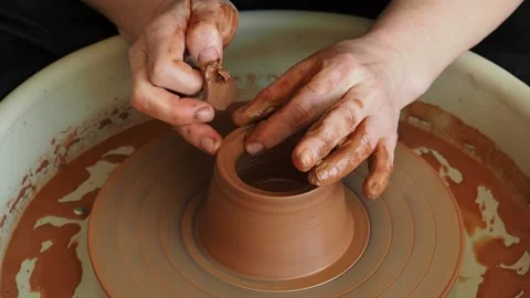 Hands of a master potter shape a red clay product on a potter's wheel Stock Footage 235758993