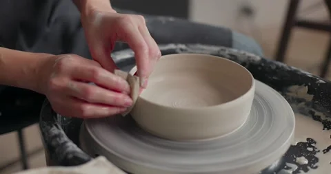 Hands of a master potter working on a potter's wheel, forming a bowl of clay Stock Footage 155814524