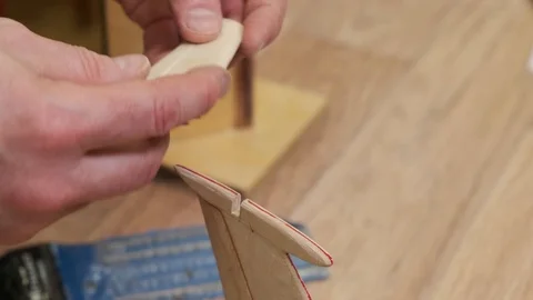 Hands match wooden stabilizer on soviet airplane model fin Stock Footage 127375317