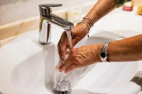 Hands of mature woman rinsing the soap in the sink Stock Photos