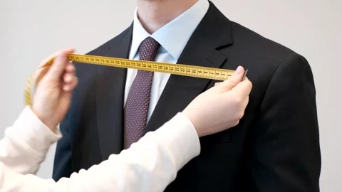 Hands measure jacket with centimeter tape on gray background, front view. Stock Footage 302943504